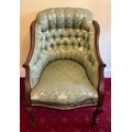A mahogany framed deep button back upholstered armchair on front cabriole legs and porcelain casters... 