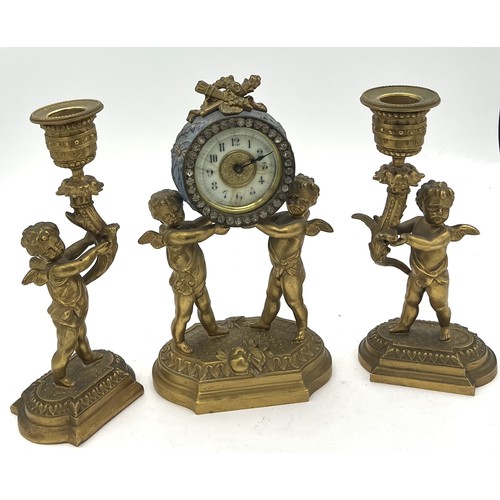 1021 - Ormolu clock garniture. 20cm h. Two cherub candlesticks and clock with enamelled face.