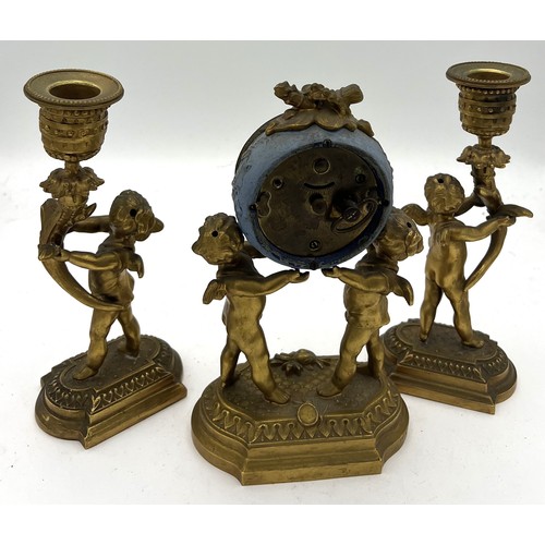 1021 - Ormolu clock garniture. 20cm h. Two cherub candlesticks and clock with enamelled face.