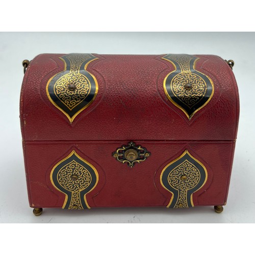 1043 - Red leather covered casket containing two glass and gilt metal scent bottles with painted tops and i... 