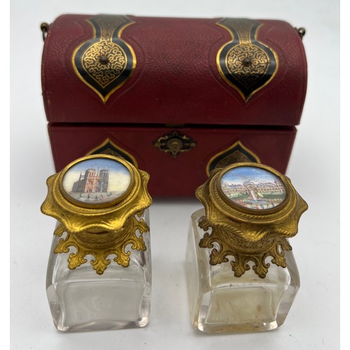 1043 - Red leather covered casket containing two glass and gilt metal scent bottles with painted tops and i... 