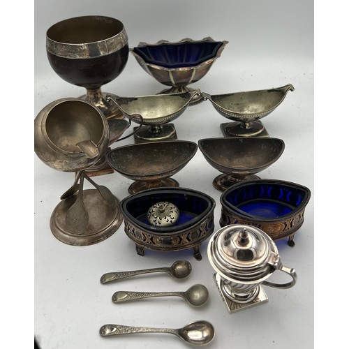 683 - A quantity of silver plated salts, a white metal mounted coconut cup, mustard pot, tennis racket ash... 