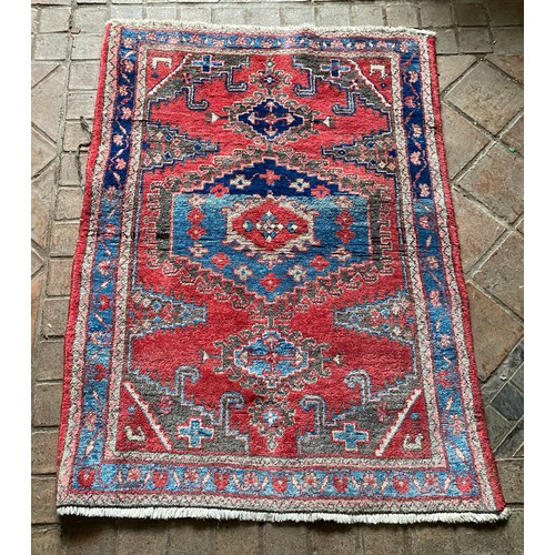 957 - A wool rug with red and blue ground geometric design. 142 x 103cm.