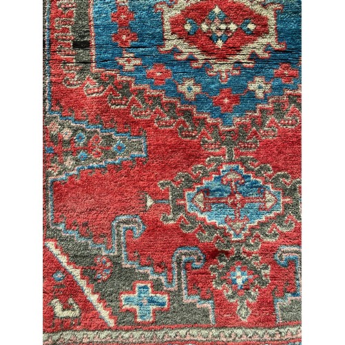 957 - A wool rug with red and blue ground geometric design. 142 x 103cm.