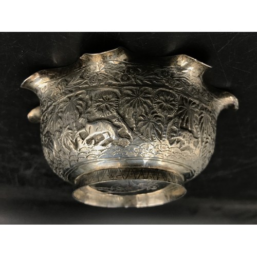 745 - An Indian silver bowl relief embossed decoration depicting elephant, tiger, figure, trees and other ... 