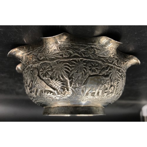 745 - An Indian silver bowl relief embossed decoration depicting elephant, tiger, figure, trees and other ... 