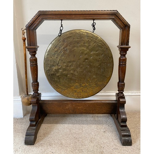 995 - A 20thC large oak dinner gong with striker measuring 71 h x 58 w x 33cm d, brass gong 41cm d.