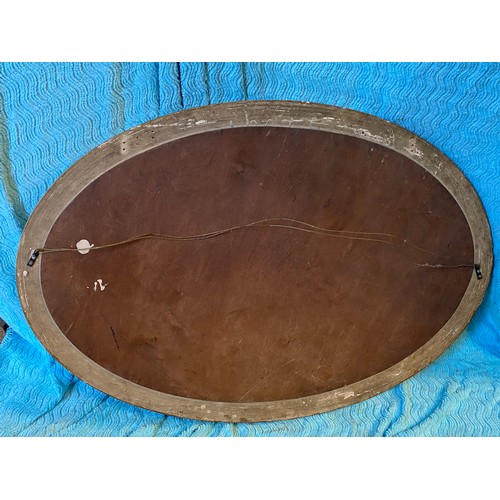 952 - An oval gilt framed mirror. 67 h x 96cm w.