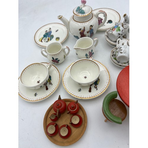 142 - Two miniature tea services and a vintage wooden dolls house table 8cm d, chairs and tea service. 
To... 