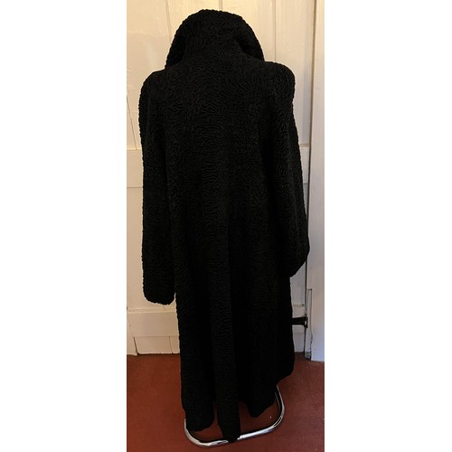 871 - A vintage black astrakhan coat (underarm to underarm approximately 60cm.) with matching hat and silk... 