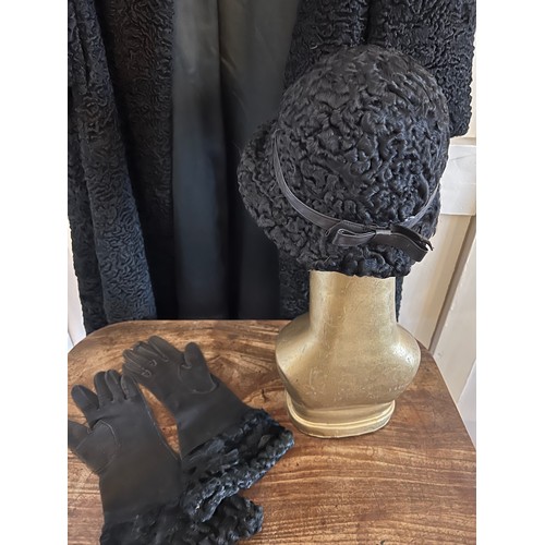 871 - A vintage black astrakhan coat (underarm to underarm approximately 60cm.) with matching hat and silk... 