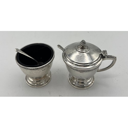 762 - A cased cruet set comprising silver mustard pot and salt and pepper, with original spoons and liners... 