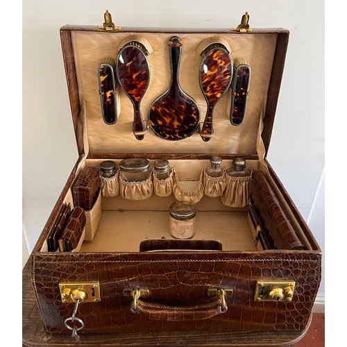 975 - A superb quality early 20thC crocodile fully fitted travelling dressing case. This comes with the or... 