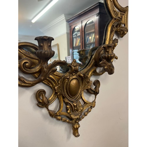 954 - A pair of 18thC ornate carved gilt wood and gesso wall mirrors with two candle sconces. 112cm h x 69... 