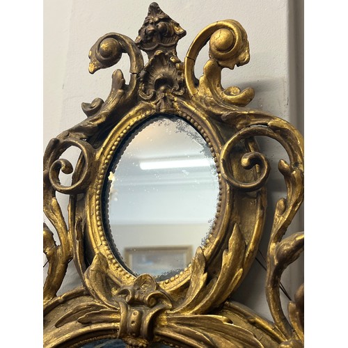 954 - A pair of 18thC ornate carved gilt wood and gesso wall mirrors with two candle sconces. 112cm h x 69... 