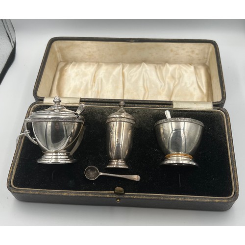 762 - A cased cruet set comprising silver mustard pot and salt and pepper, with original spoons and liners... 