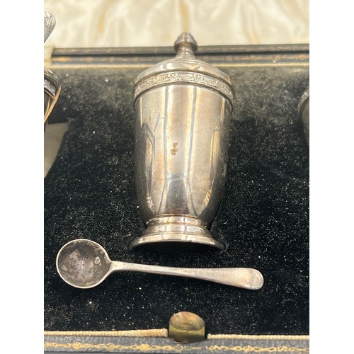 762 - A cased cruet set comprising silver mustard pot and salt and pepper, with original spoons and liners... 