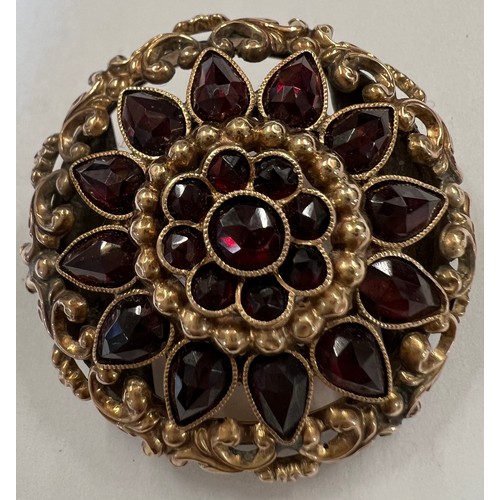 413A - A 9 carat gold garnet set brooch. 3cm d with brass fitting to rear.