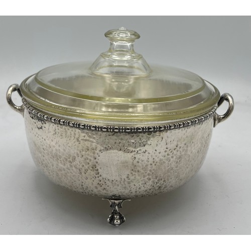 788 - A twin handled hammered silver dish holder raised on paw feet with lidded Pyrex dish. Birmingham 192... 