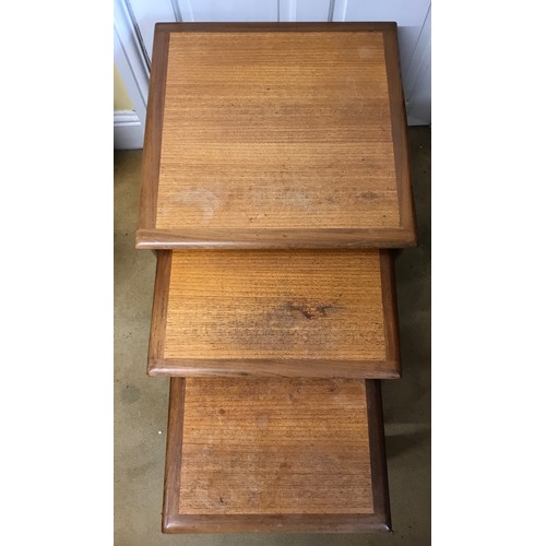 18 - A mid century nest of three G-Plan tables, solid teak frames each supported by a quadrille type base... 