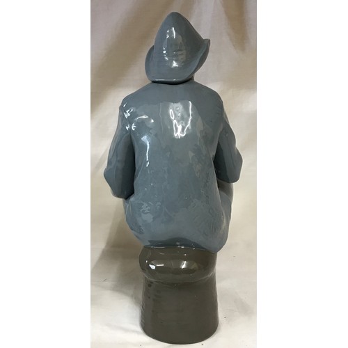 225 - A large Nao figure modelled as a fisherman seated smoking a pipe, 39cm h.