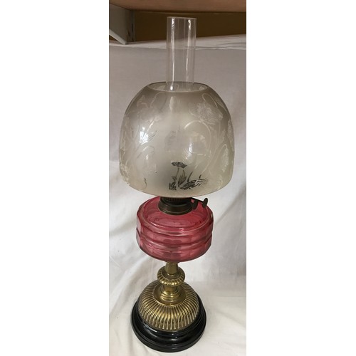 744 - Paraffin oil lamp, with cranberry coloured reservoir, etched shade on brass base, circular moulded b... 