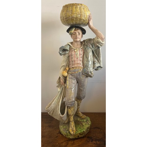 243 - A continental figure of a young man carrying a basket on his head. 69cm h.