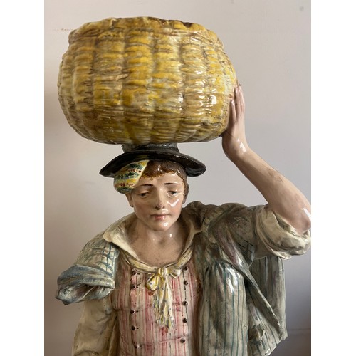 243 - A continental figure of a young man carrying a basket on his head. 69cm h.