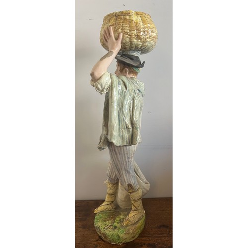 243 - A continental figure of a young man carrying a basket on his head. 69cm h.