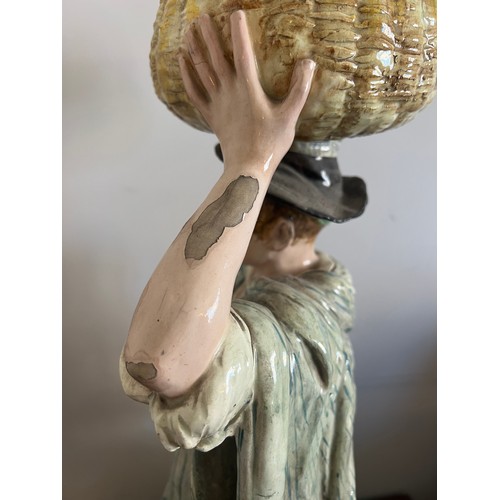 243 - A continental figure of a young man carrying a basket on his head. 69cm h.