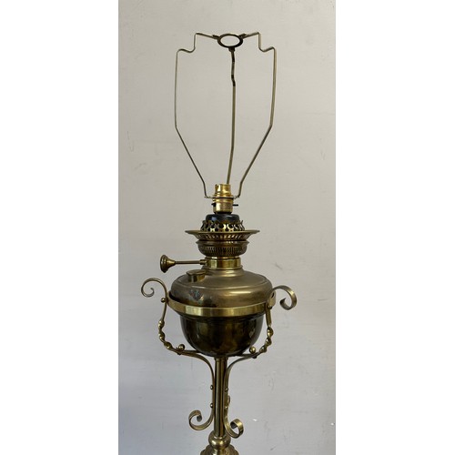 750 - A decorative scrolled brass standard lamp with shade converted from an oil lamp. 151cm h without fit... 