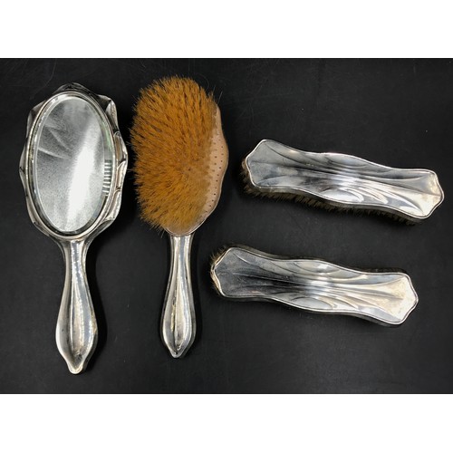 849 - A silver backed vanity set comprising of three brushes and a hand mirror hand brushes hallmarked 191... 