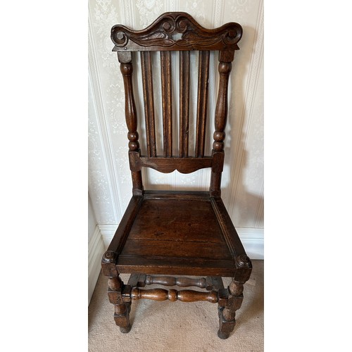 130 - An 18thC oak hall chair with slatted back and carved top rail. Height to back 107cm.