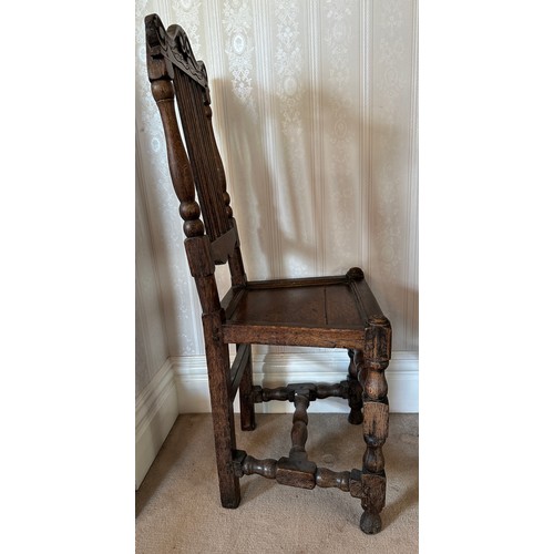 130 - An 18thC oak hall chair with slatted back and carved top rail. Height to back 107cm.