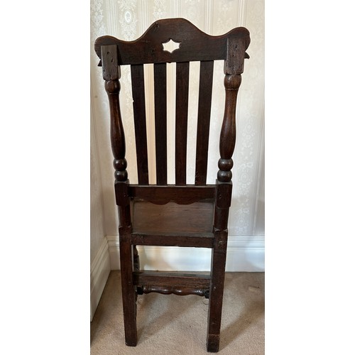 130 - An 18thC oak hall chair with slatted back and carved top rail. Height to back 107cm.