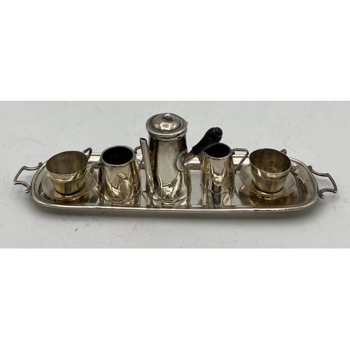 861 - A miniature silver coffee service on tray, comprising coffee pot, two cups and saucers, milk and sug... 