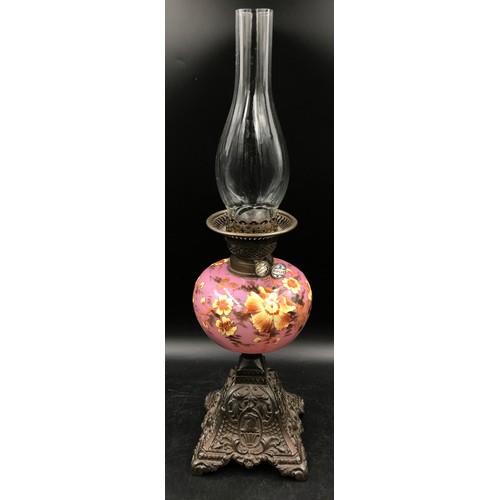 761 - An oil lamp decorated in hand painted yellow flowers on a pink background marked Duplex with clear g... 