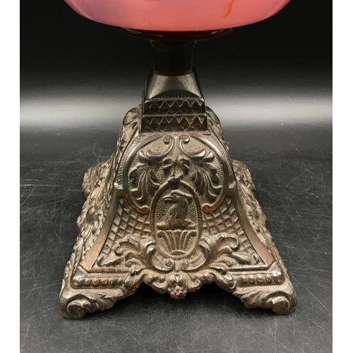 761 - An oil lamp decorated in hand painted yellow flowers on a pink background marked Duplex with clear g... 