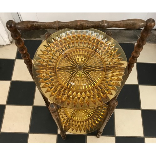 143 - A two tier wooden folding cake stand with amber glass plates. Plates 30cm d. Cake stand 68cm h.