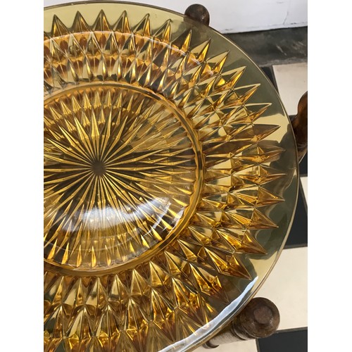 143 - A two tier wooden folding cake stand with amber glass plates. Plates 30cm d. Cake stand 68cm h.