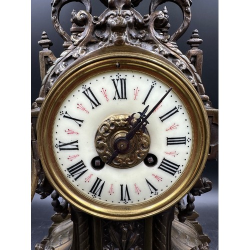 1043 - A large ornate brass mantle clock with white enamel face. 49cm h.