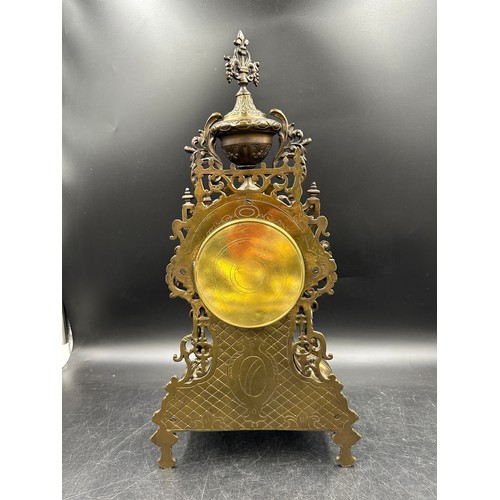 1043 - A large ornate brass mantle clock with white enamel face. 49cm h.