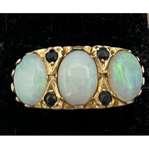 478 - A 9 carat gold ring set with three opals and four sapphires. Size N. Weight 4.2gm.