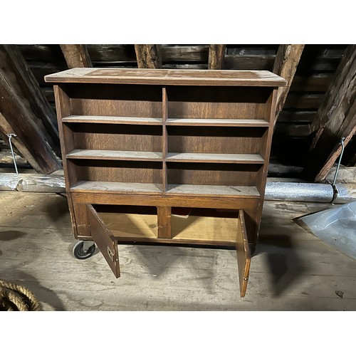 181 - An oak double sided library book case on wheels with cupboards to one side and top storage compartme... 