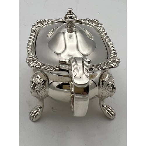 62 - A silver mustard pot, the body raised on four lion mask and paw feet, gadrooned top rim with single ... 