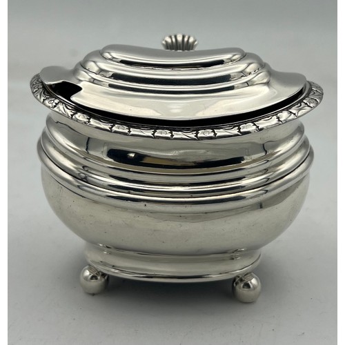 64 - A large silver ovoid mustard pot with blue glass liner, raised on four ball feet, three embossed ban... 