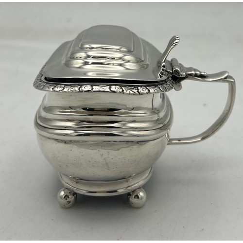 64 - A large silver ovoid mustard pot with blue glass liner, raised on four ball feet, three embossed ban... 