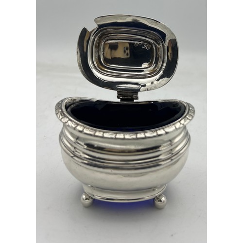 64 - A large silver ovoid mustard pot with blue glass liner, raised on four ball feet, three embossed ban... 