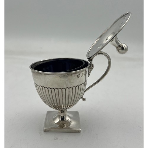 66 - An urn shaped silver mustard pot on a square base, the lower half of the body fluted, the lid rising... 