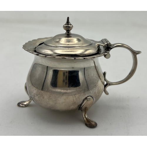 67 - A lidded silver mustard pot raised on three hoof feet and blue glass liner, Chester 1904. Maker Geor... 